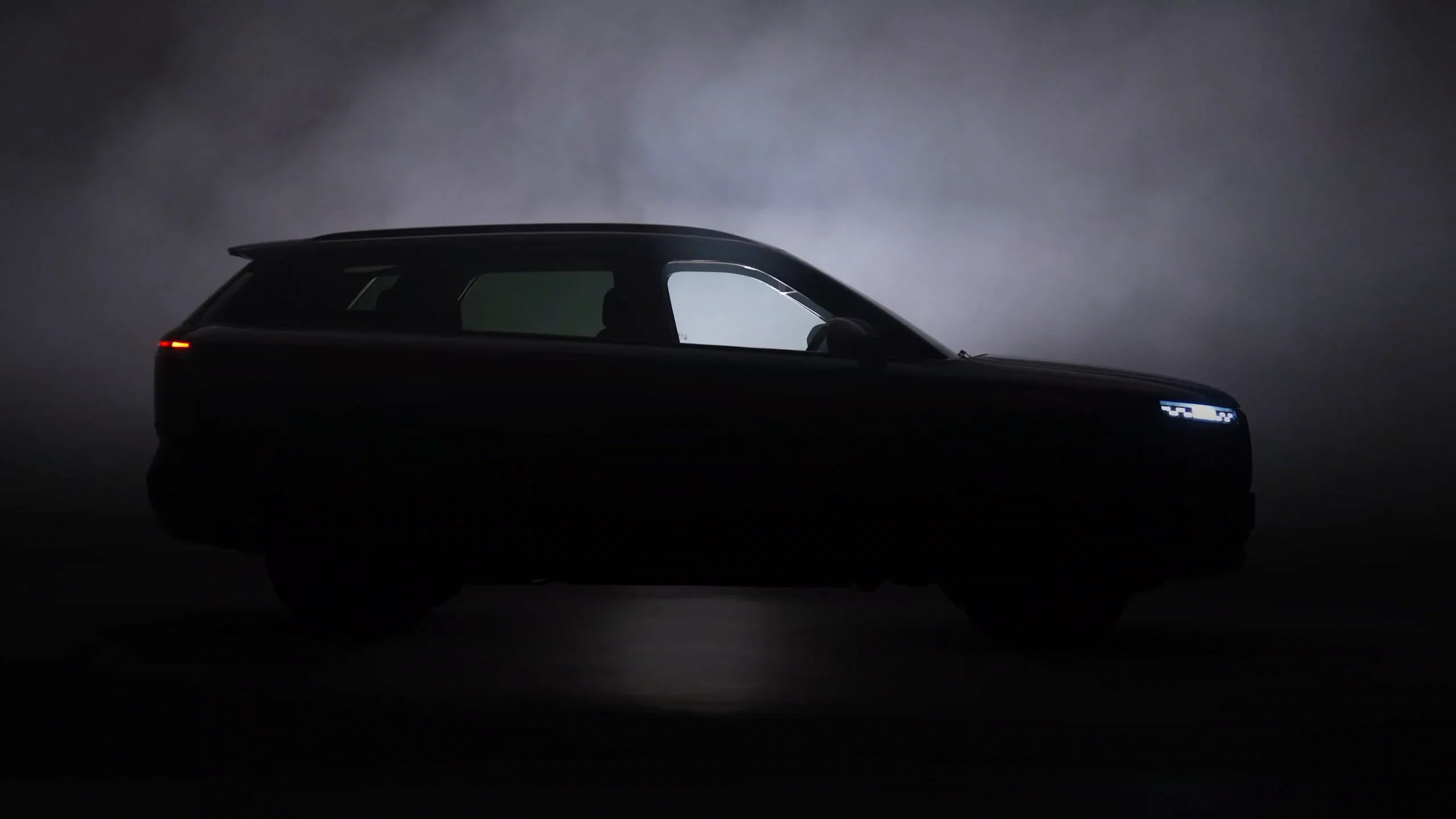 Silhouette of the Jaecoo J7 Black Edition in fog, headlights on